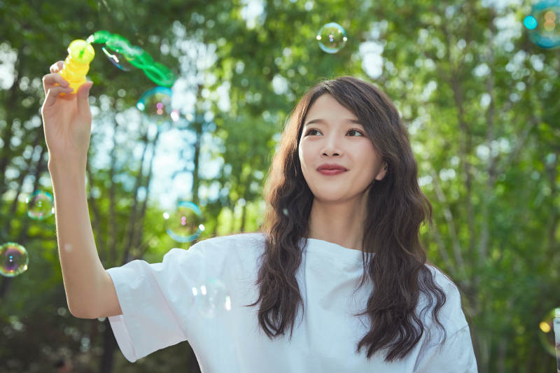 户外公园里玩吹泡泡的可爱亚洲少女图片