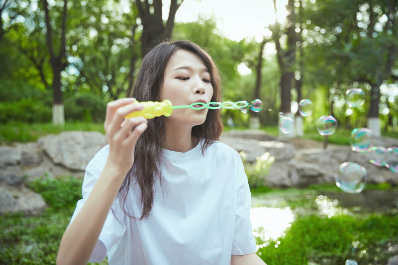 户外公园里玩吹泡泡的可爱亚洲少女图片