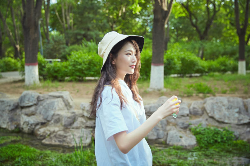 户外公园里玩吹泡泡的可爱亚洲少女图片