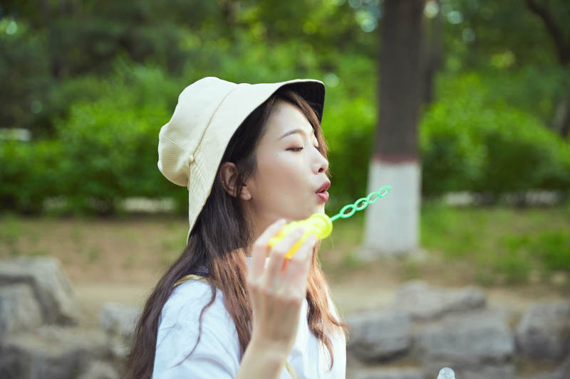 户外公园里玩吹泡泡的可爱亚洲少女图片
