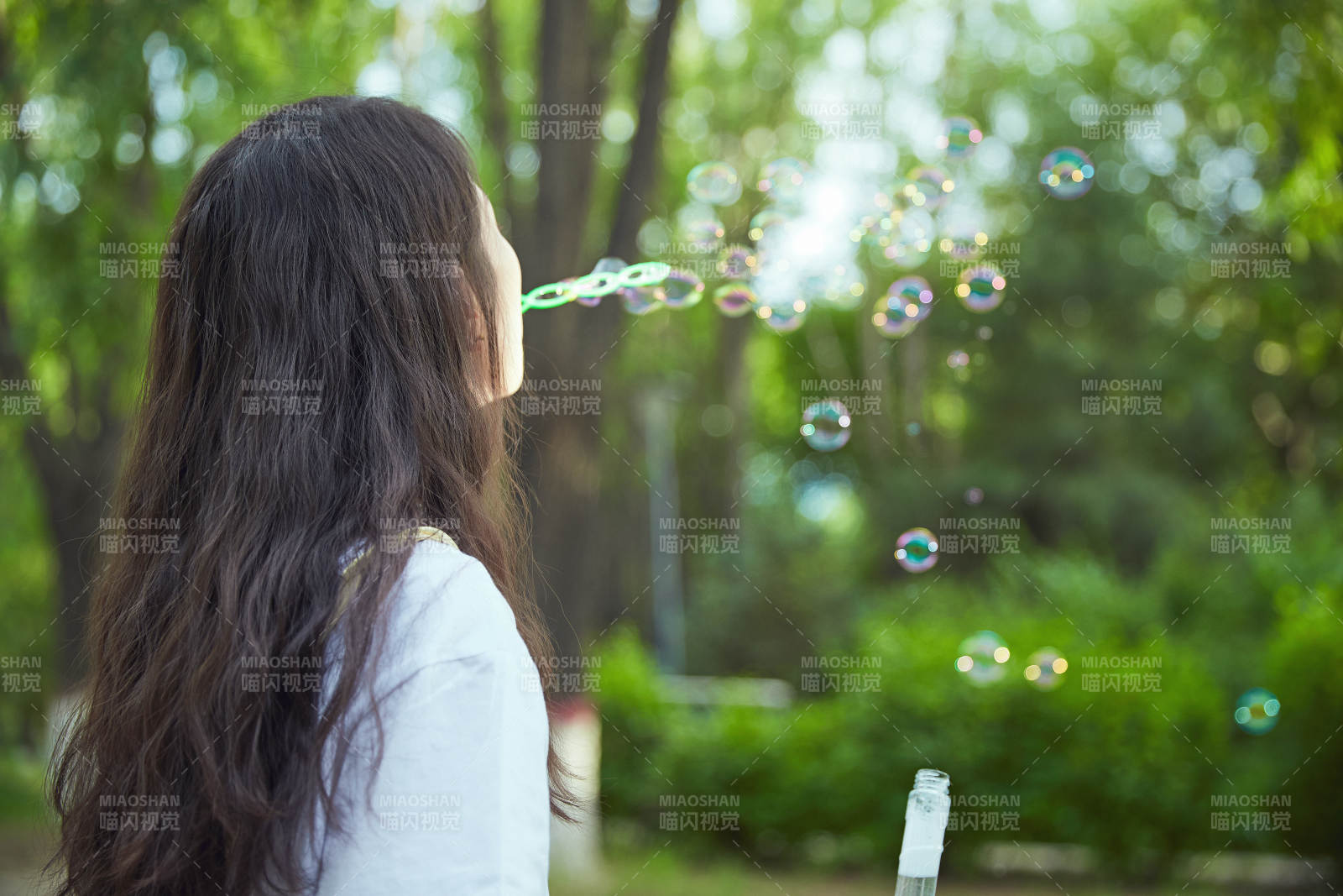 户外公园里玩吹泡泡的可爱亚洲少女图片