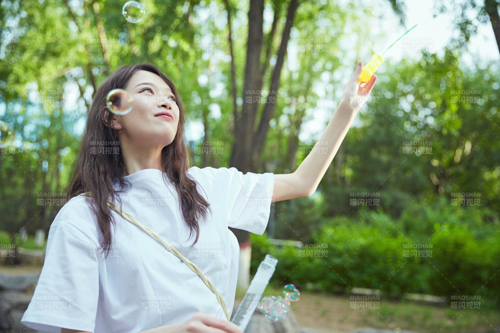 户外公园里玩吹泡泡的可爱亚洲少女图片