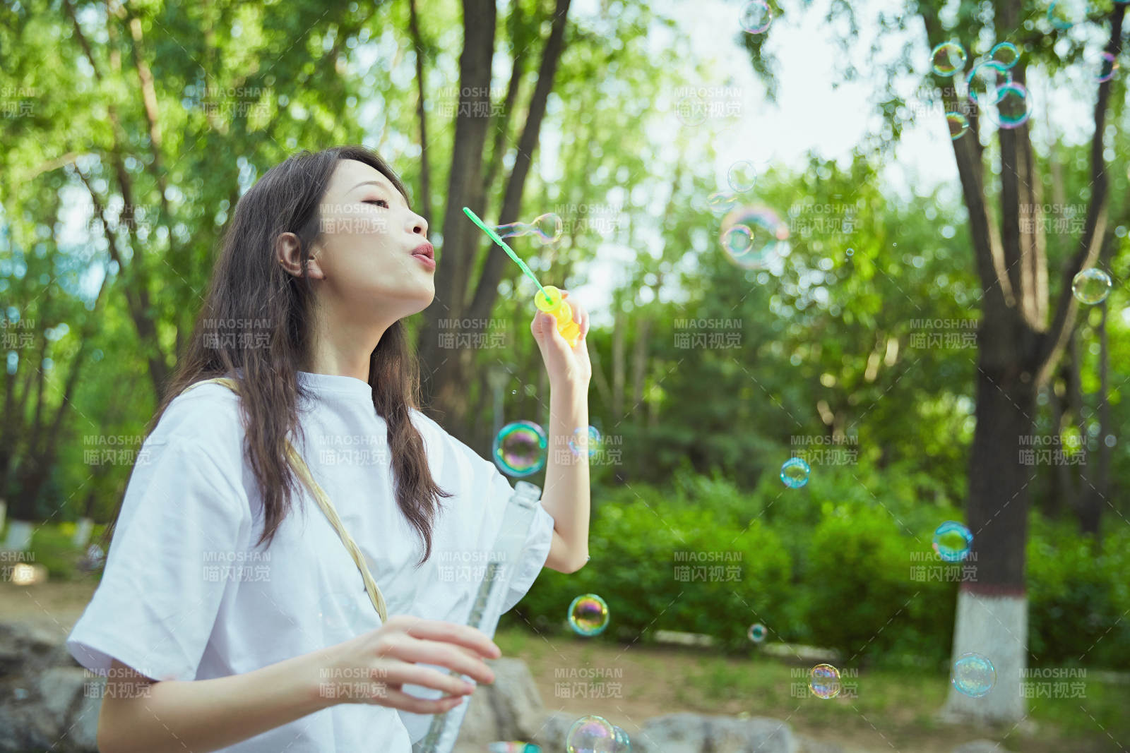 户外公园里玩吹泡泡的可爱亚洲少女图片