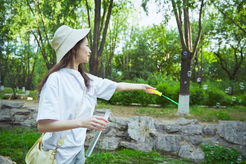 户外公园里玩吹泡泡的可爱亚洲少女图片