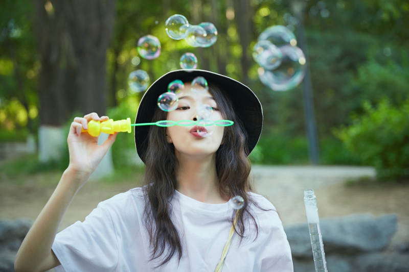 户外公园里玩吹泡泡的可爱亚洲少女图片