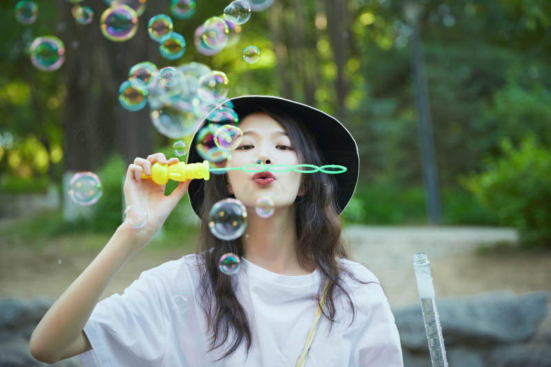 户外公园里玩吹泡泡的可爱亚洲少女图片