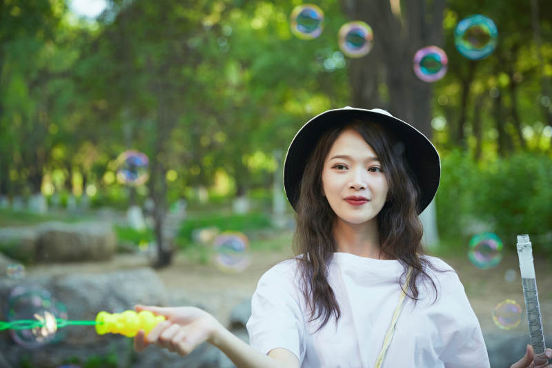 户外公园里玩吹泡泡的可爱亚洲少女图片