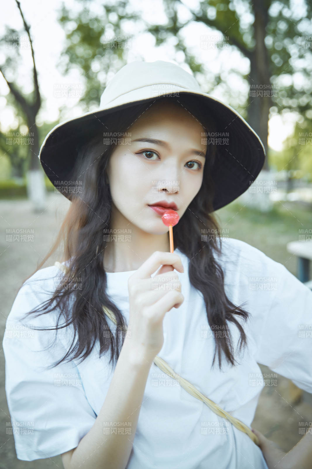 公园湖边吃棒棒糖的亚洲可爱少女图片