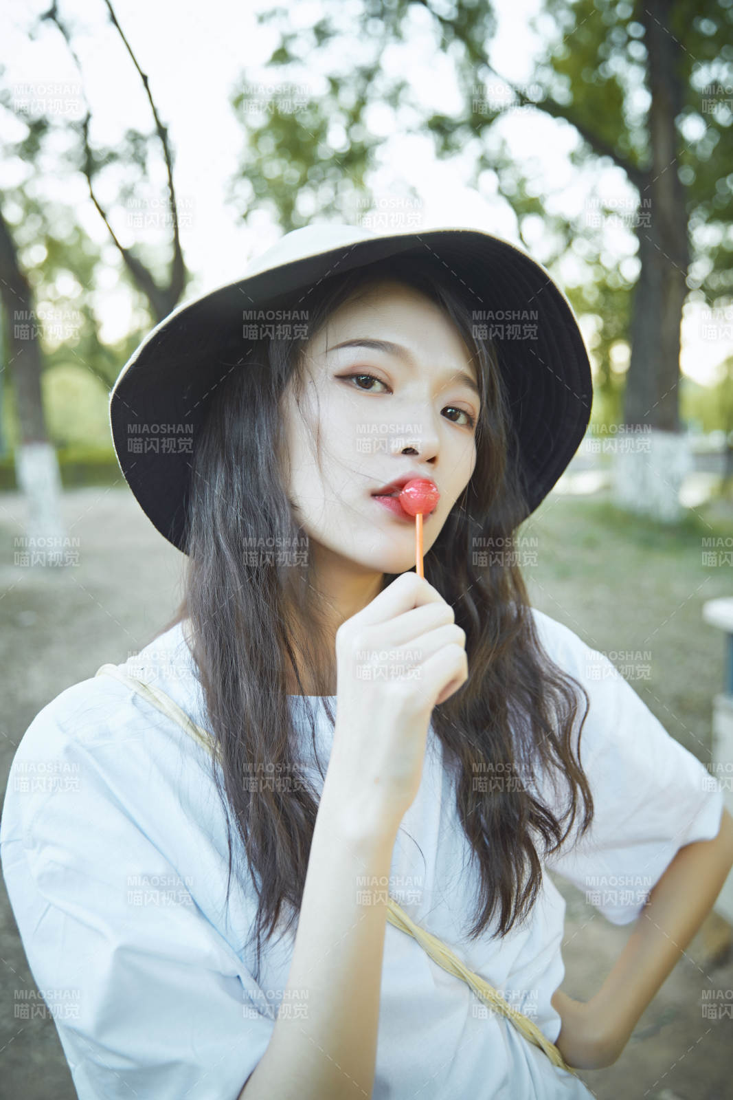 公园湖边吃棒棒糖的亚洲可爱少女图片