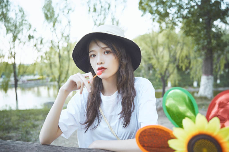 公园湖边吃棒棒糖的亚洲可爱少女图片