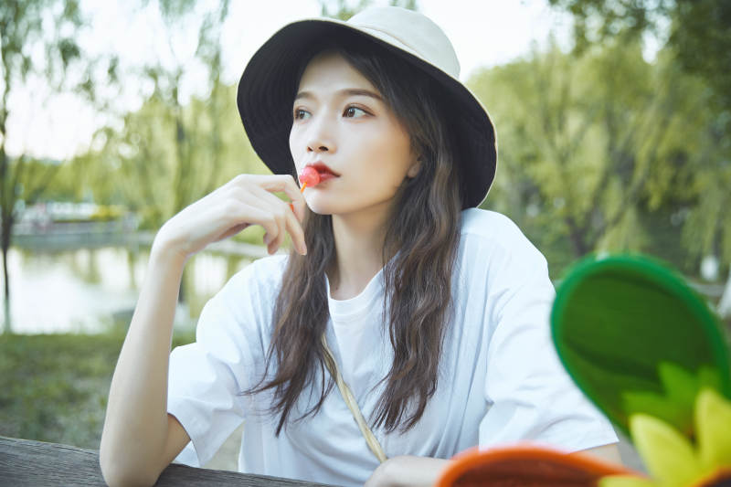公园湖边吃棒棒糖的亚洲可爱少女图片