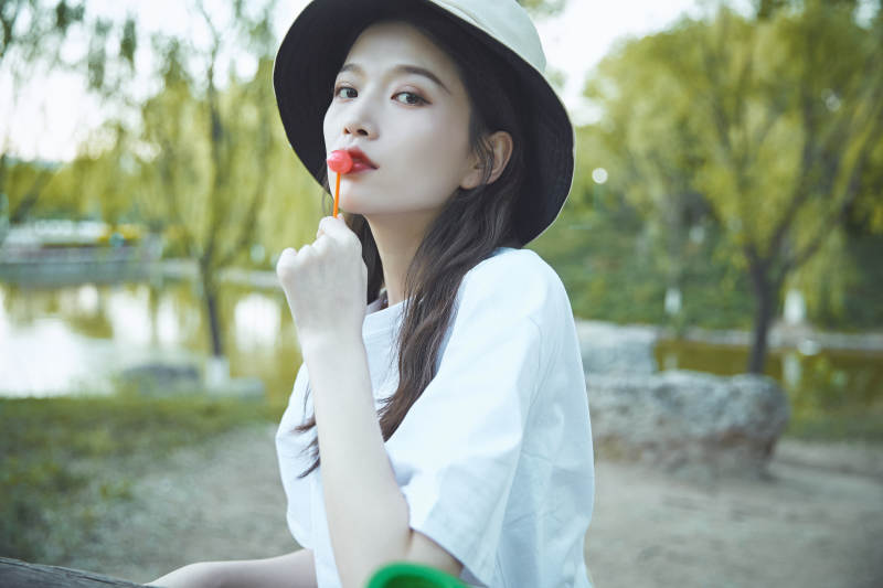 公园湖边吃棒棒糖的亚洲可爱少女图片
