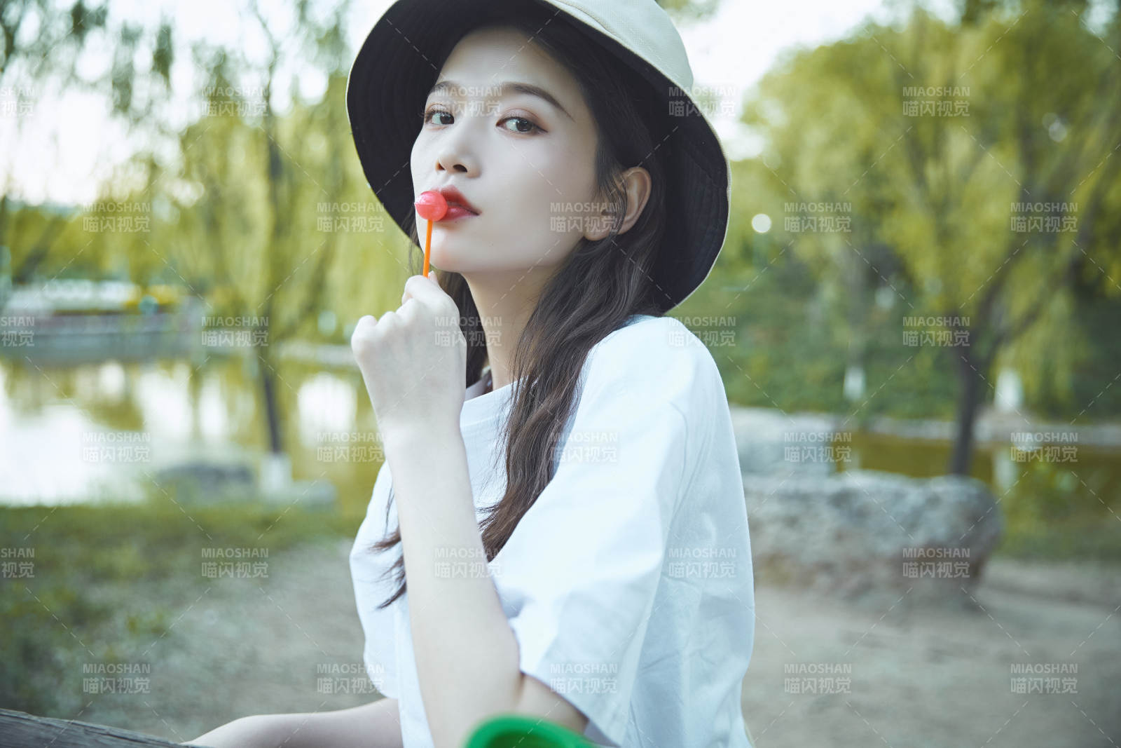 公园湖边吃棒棒糖的亚洲可爱少女图片