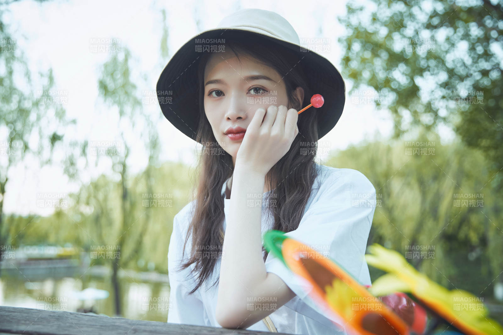 公园湖边吃棒棒糖的亚洲可爱少女图片