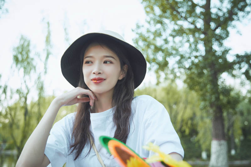 公园湖边吃棒棒糖的亚洲可爱少女图片