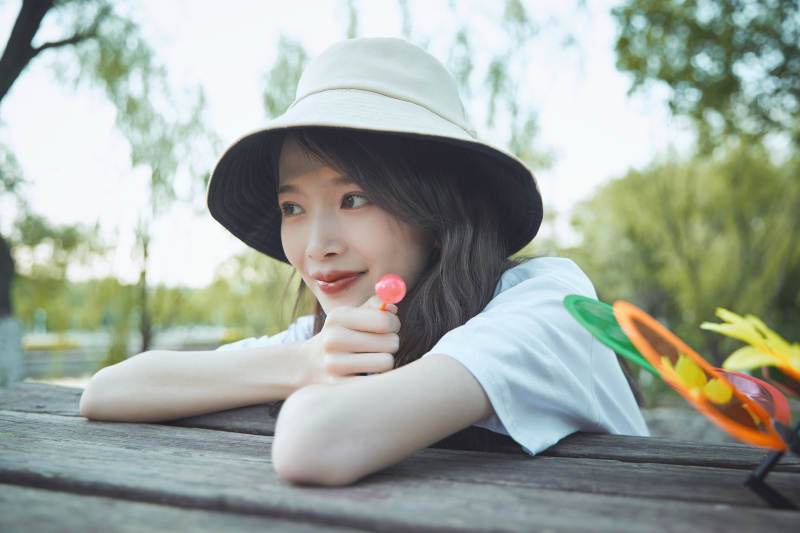 公园湖边吃棒棒糖的亚洲可爱少女图片