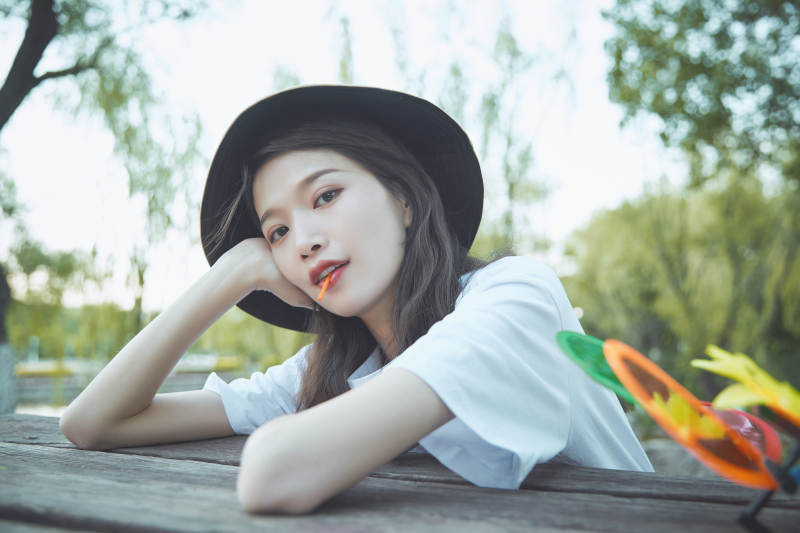 公园湖边吃棒棒糖的亚洲可爱少女图片