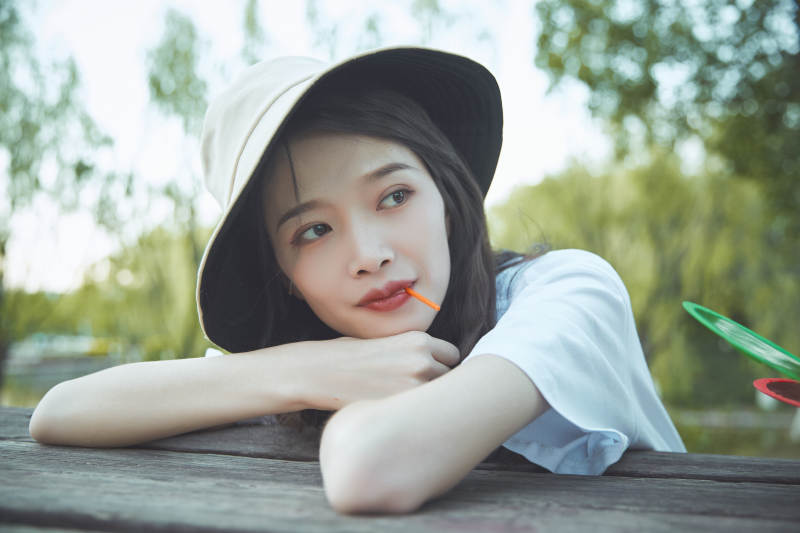 公园湖边吃棒棒糖的亚洲可爱少女图片