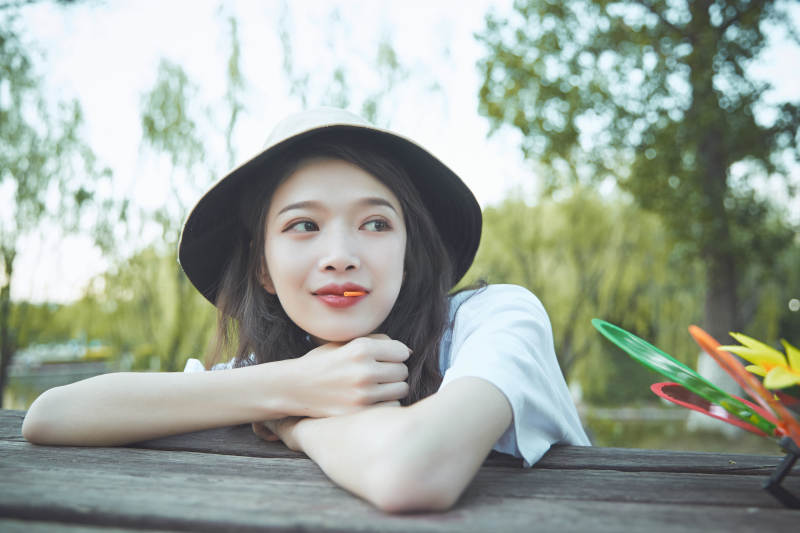 公园湖边吃棒棒糖的亚洲可爱少女图片