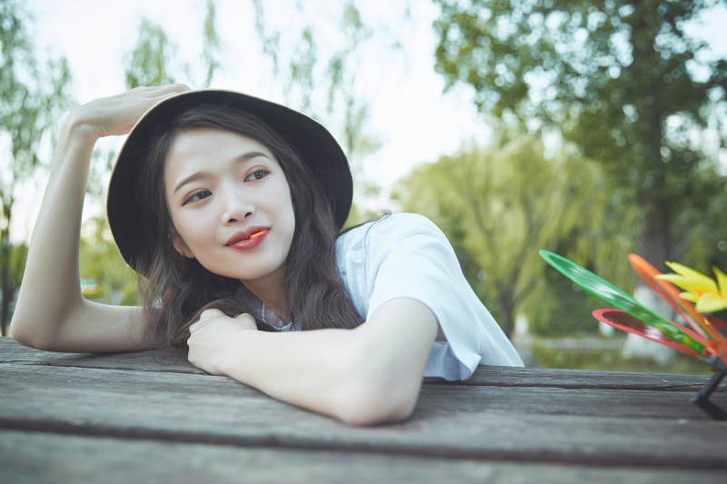 公园湖边吃棒棒糖的亚洲可爱少女图片