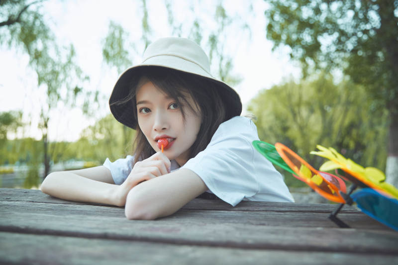 公园湖边吃棒棒糖的亚洲可爱少女图片