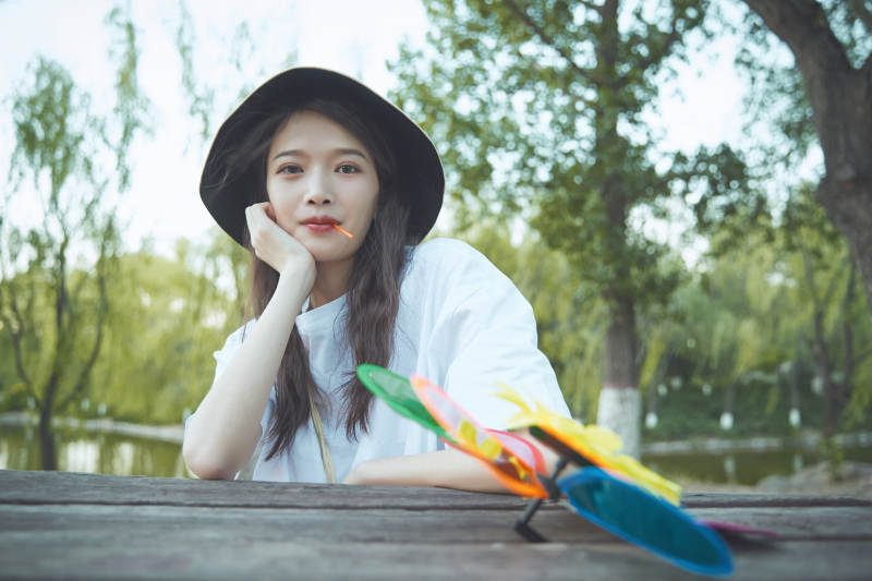 公园湖边吃棒棒糖的亚洲可爱少女图片