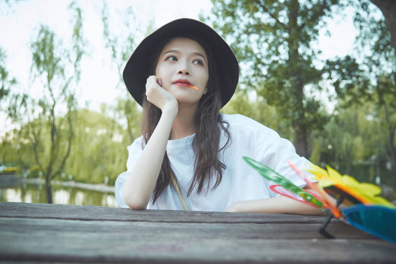 公园湖边吃棒棒糖的亚洲可爱少女图片