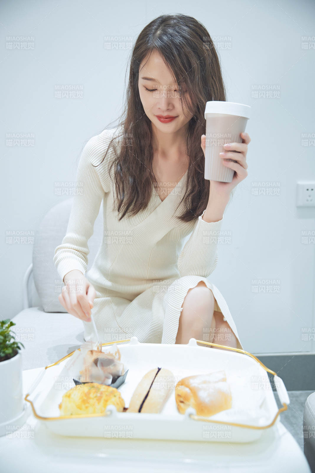 在烘焙店吃面包喝牛奶的可爱亚洲少女图片