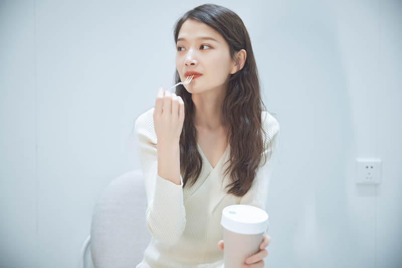 在烘焙店吃面包喝牛奶的可爱亚洲少女图片