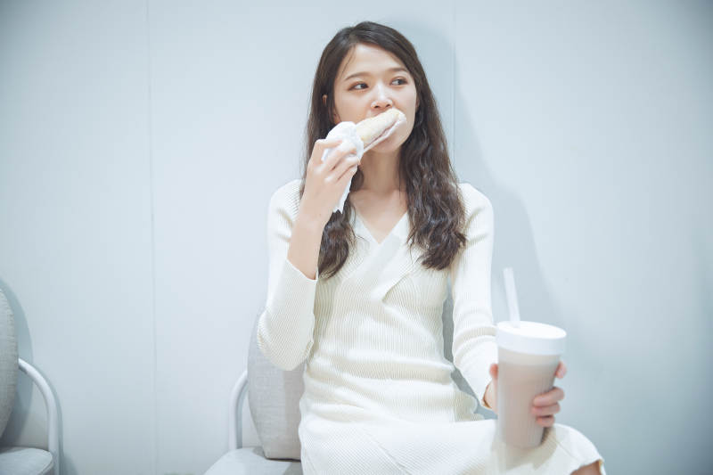 在烘焙店吃面包喝牛奶的可爱亚洲少女图片