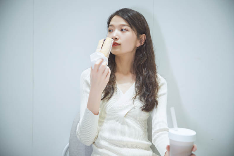 在烘焙店吃面包喝牛奶的可爱亚洲少女图片