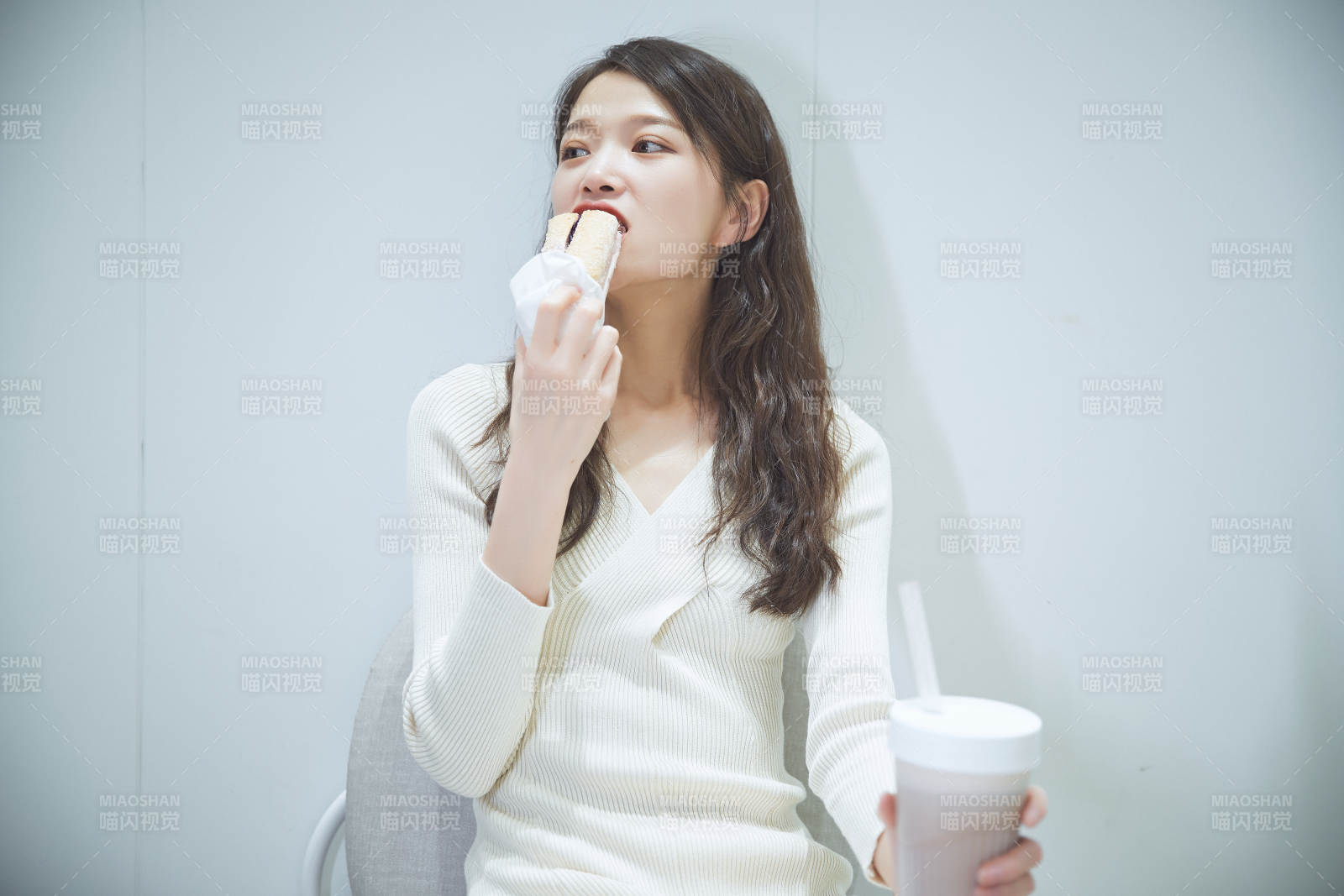 在烘焙店吃面包喝牛奶的可爱亚洲少女图片