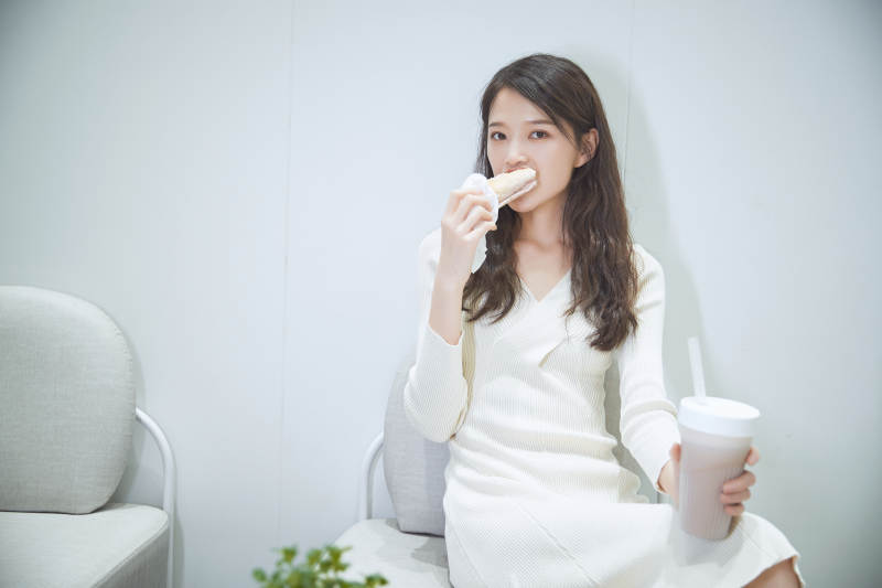 在烘焙店吃面包喝牛奶的可爱亚洲少女图片