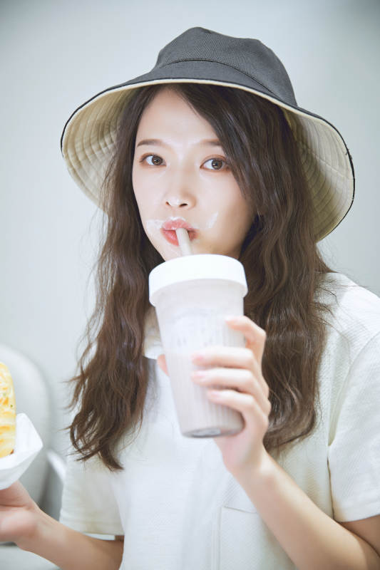 在烘焙店吃面包喝牛奶的可爱亚洲少女图片