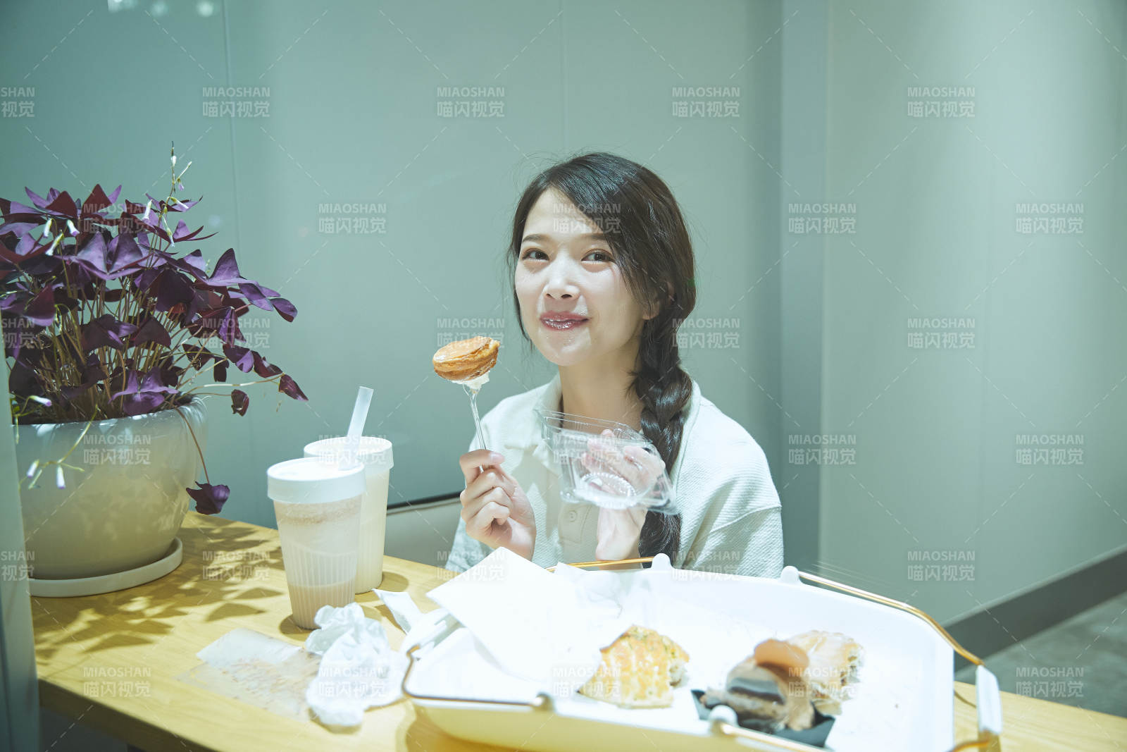 在烘焙店吃面包喝牛奶的可爱亚洲少女图片