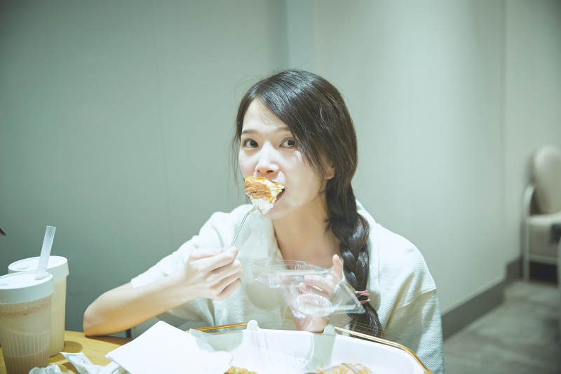 在烘焙店吃面包喝牛奶的可爱亚洲少女图片