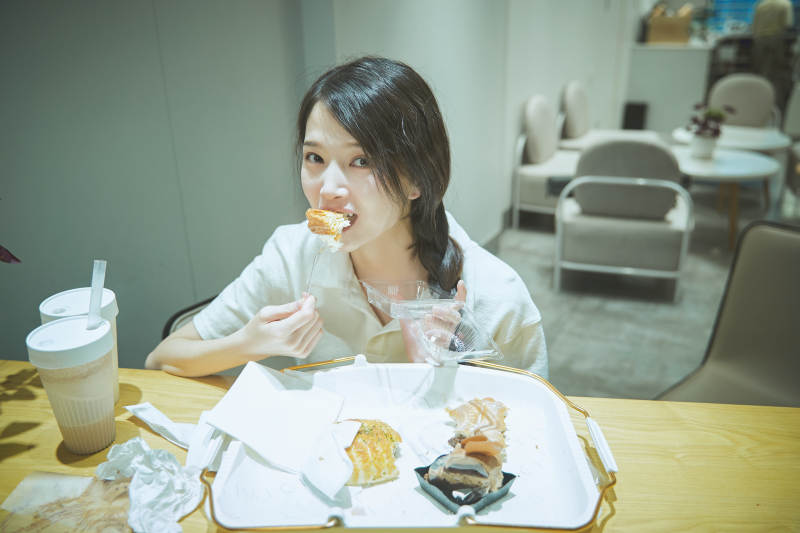 在烘焙店吃面包喝牛奶的可爱亚洲少女图片