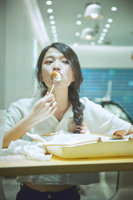 在烘焙店吃面包喝牛奶的可爱亚洲少女图片