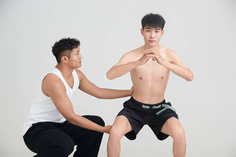 年轻男子在教练的指导下健身图片