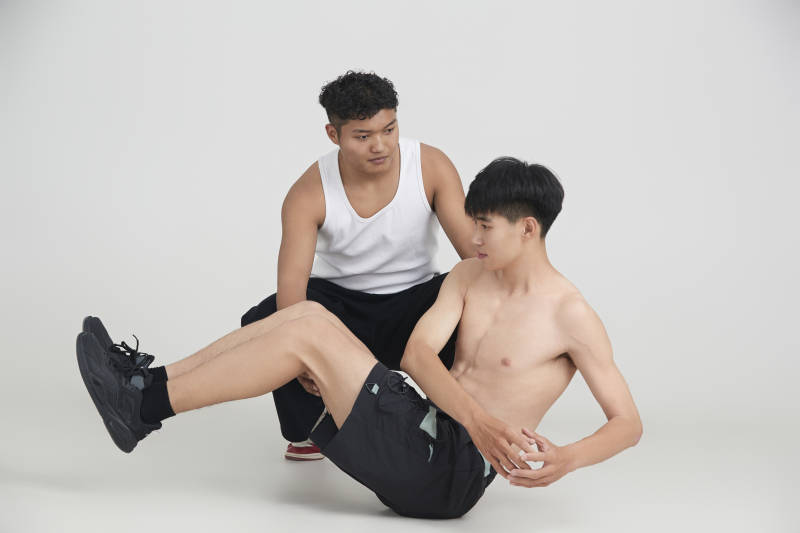 年轻男子在教练的指导下健身图片