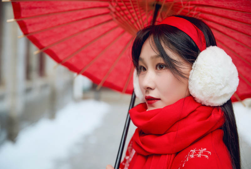 雪后在老城古巷穿着喜庆服饰的亚洲少女图片