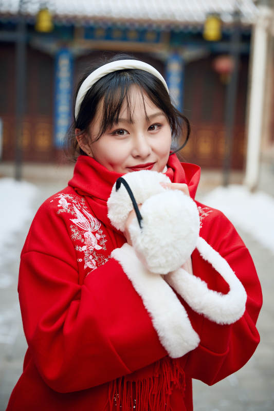 雪后在老城古巷穿着喜庆服饰的亚洲少女图片