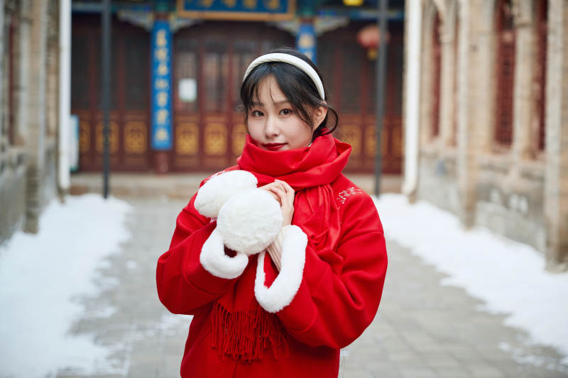 雪后在老城古巷穿着喜庆服饰的亚洲少女图片