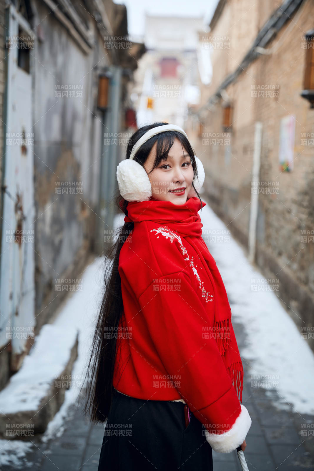 雪后在老城古巷穿着喜庆服饰的亚洲少女图片