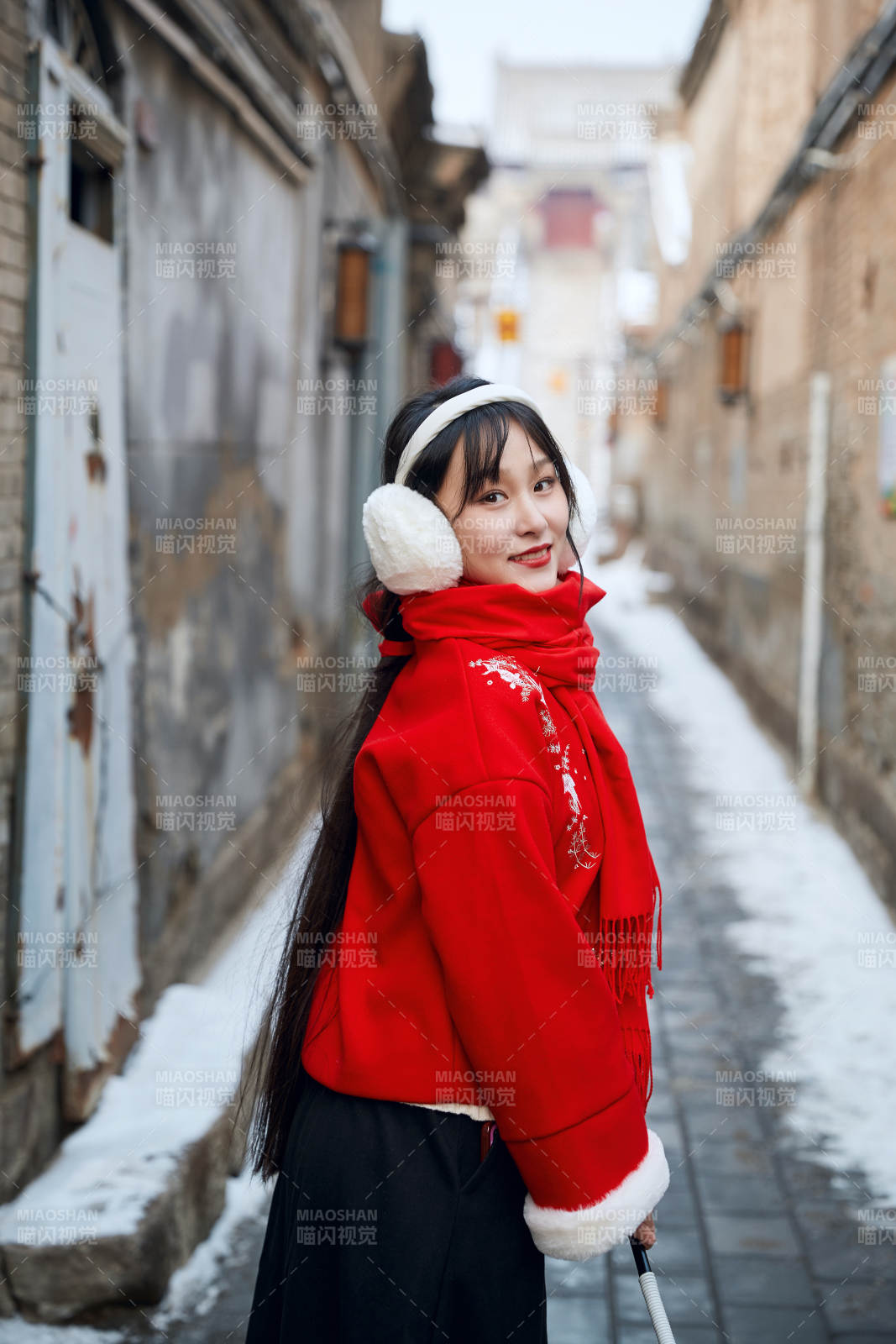 雪后在老城古巷穿着喜庆服饰的亚洲少女图片