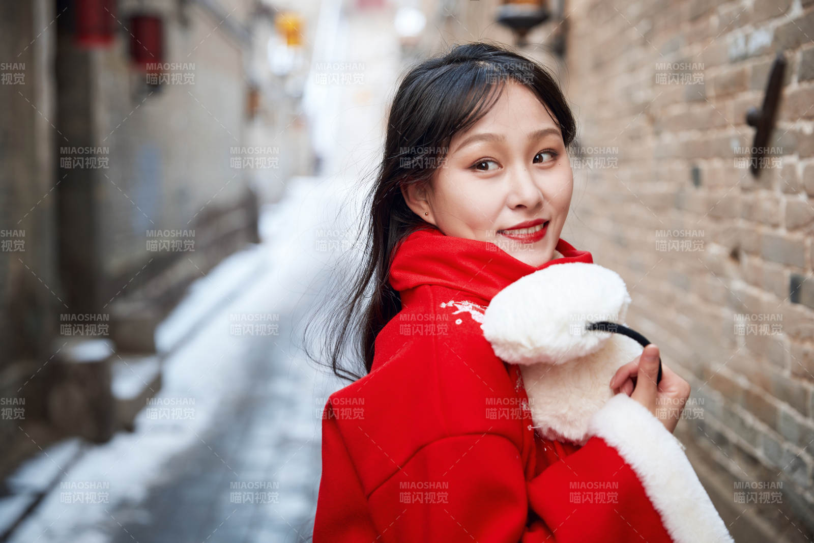 雪后在老城古巷穿着喜庆服饰的亚洲少女图片