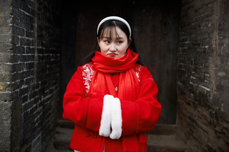 雪后在老城古巷穿着喜庆服饰的亚洲少女图片