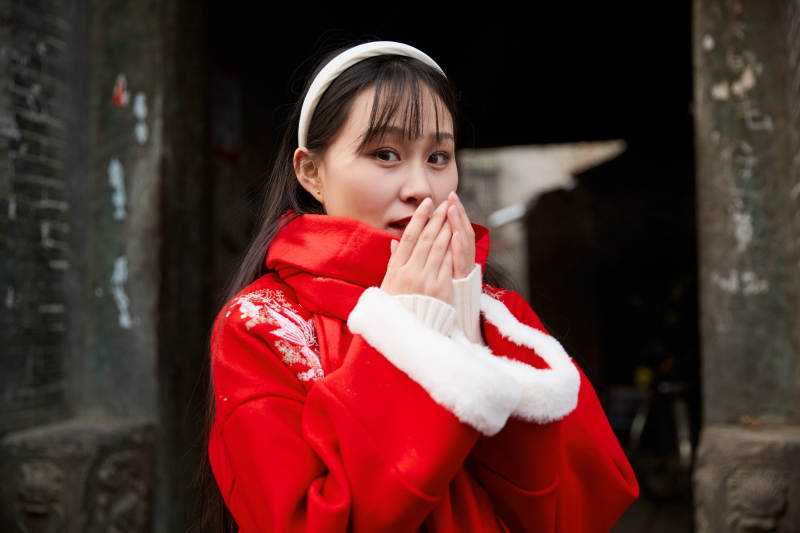 雪后在老城古巷穿着喜庆服饰的亚洲少女图片