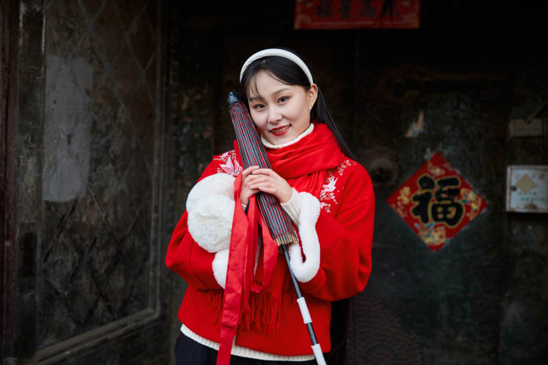 雪后在老城古巷穿着喜庆服饰的亚洲少女图片