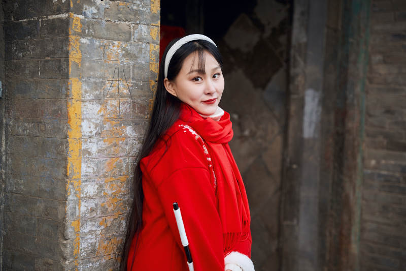 雪后在老城古巷穿着喜庆服饰的亚洲少女图片